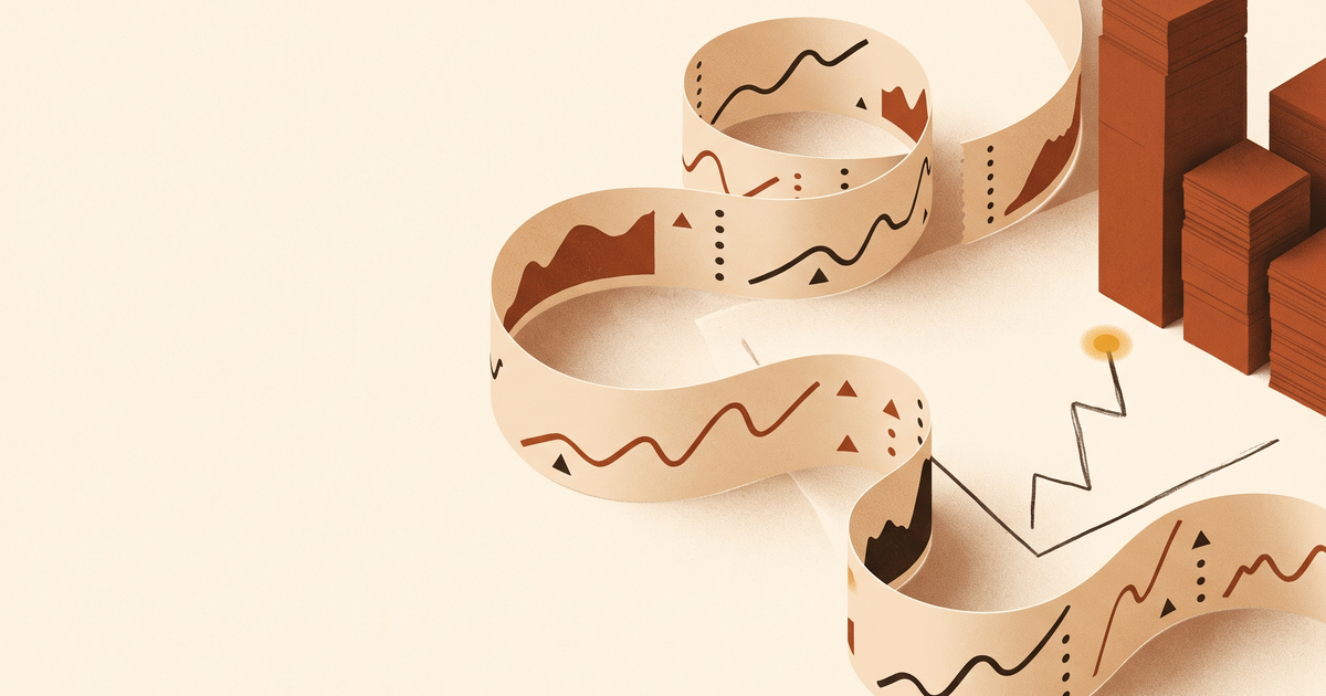 A paper stock ticker tape curling across a desk beside rust bar-chart blocks